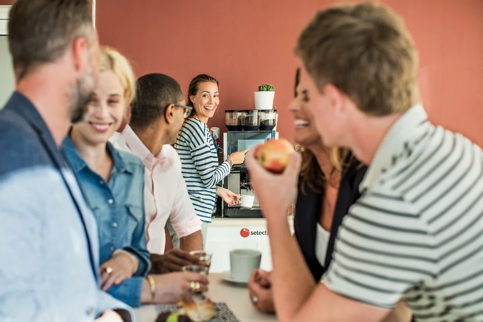 A group of people enjoying office coffee made with a tabletop coffee machine